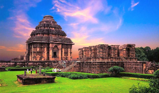 a large brick building with green grass with Konark Sun Temple in the background jigsaw puzzle